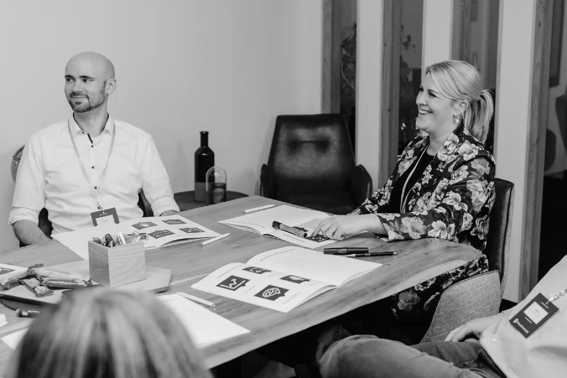 Zwei Teilnehmende lachen während des Präsentationstrainings am Seminartisch